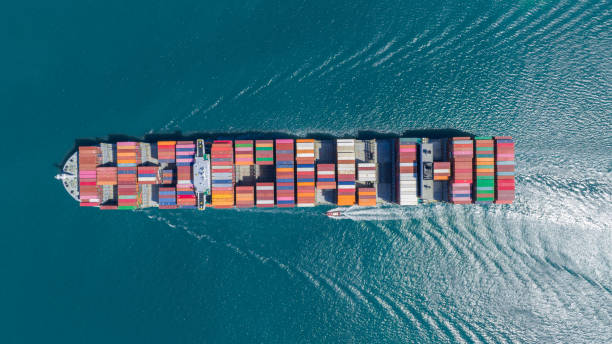 istock top view Cargo Container Ship with Tug boat carrying container and running very fast for export import cargo from container yard port to custom ,Contrail line in the ocean 1475056087