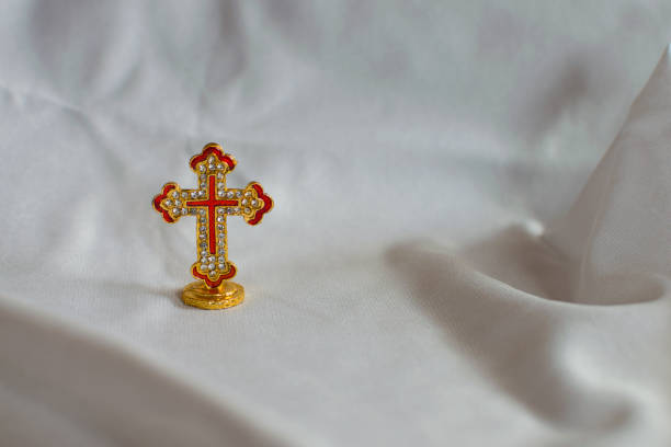 Golden cross placed on an isolated white cloth, symbolizing resurrection.