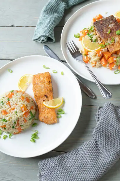 Delicious healthy dinner or lunch for healthy eating, fitness or dieting with pan fries salmon fillet. Served with brown rice and vegetables on plates with different serving variations.