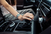 A woman behind the wheel. A young woman's hand on the gear selector in a modern car. Automatic transmission gear shift.