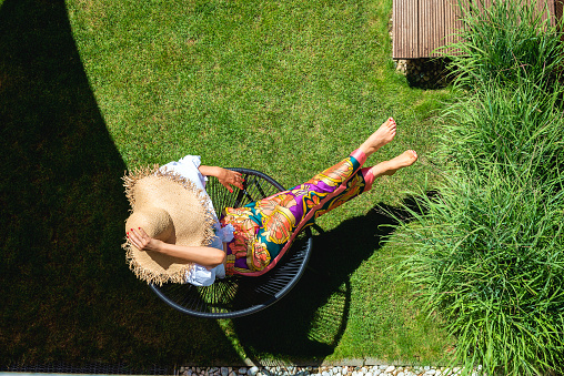 High angle shot of an urecognizable woman wearing straw hat and beachwear while relaxing outdoor.