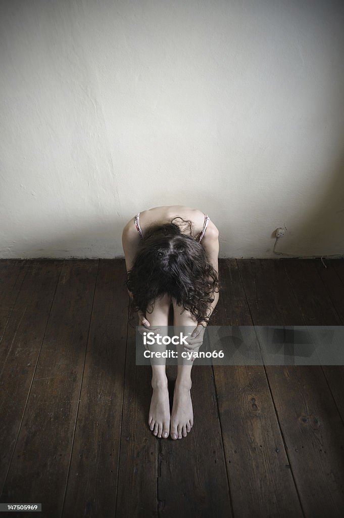 desperate young woman desperate young woman is sitting on an old wooden floor. top view Punishment Stock Photo