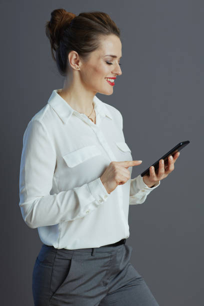 istock smiling female employee texting using phone isolated on gray 1475060265