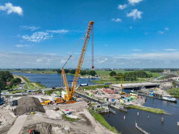 Mobile cranes at a construction site hauling new bridge sections over a waterway stock photo