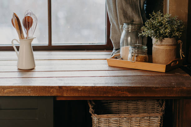 Kitchen utensils in white container on wooden table near window. Home kitchen decor. Kitchenware. Time to cook. Cutlery in room.