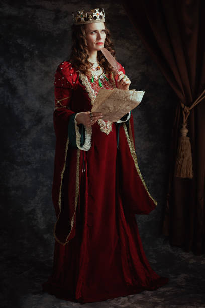 Full length portrait of pensive medieval queen in red dress Full length portrait of pensive medieval queen in red dress with parchment and crown on dark gray background. renaissance dress stock pictures, royalty-free photos & images