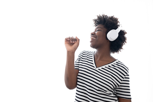 Isolated African American woman singing and listening to music on headphones