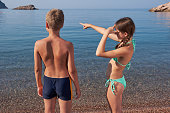 A boy and a girl look into the distance standing on the sea beach. Summer holidays on vacation