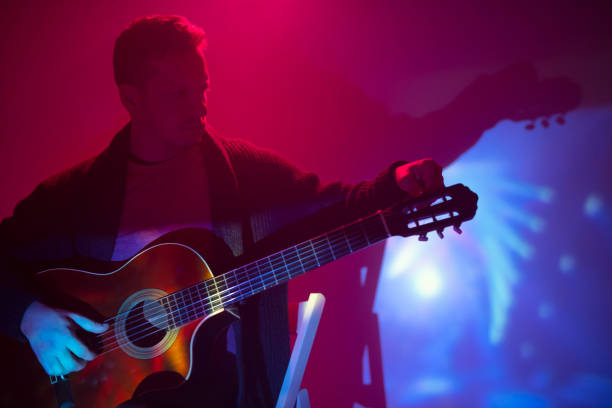 musician playing acoustic guitar in a foggy club with colorful lights. - fingerstyle imagens e fotografias de stock