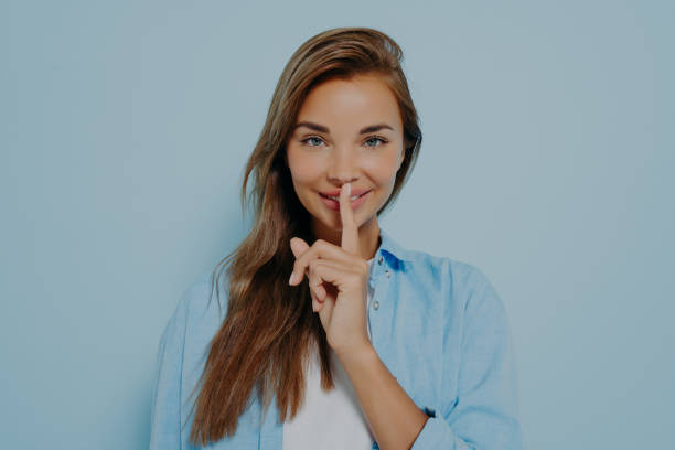 istock Beautiful woman showing shush gesture on light blue background 1475068649