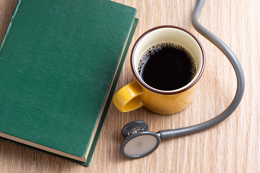 still life photography : americano coffee cup with stethoscope and textbook on wooden table