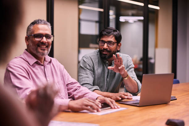 istock Smiling businessman talking with colleagues during an office meeting 1475073902