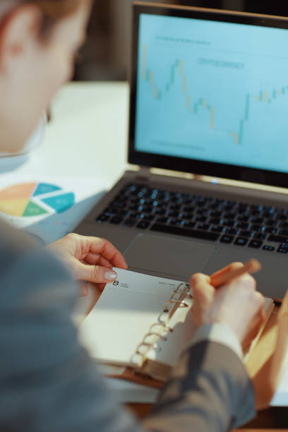 istock Seen from behind modern business woman writes in notebook 1475074035
