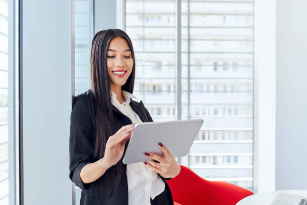 istock Smiling young businesswoman using digital tablet at modern office 1475079359