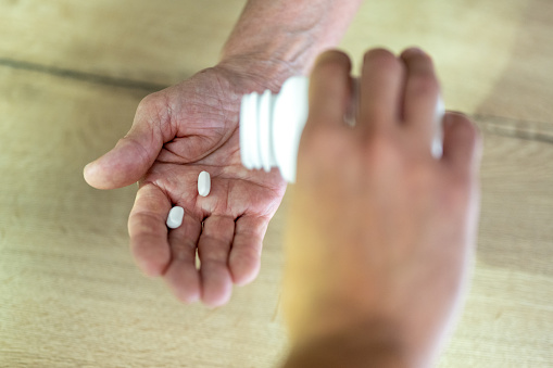 Close-up of woman's hands pouring pills on man's hand