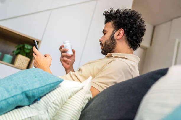 istock Man holding pill bottle and mobile 1475081492