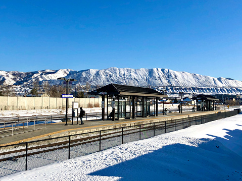 People waiting on train station at salt lake city snow capped mountains