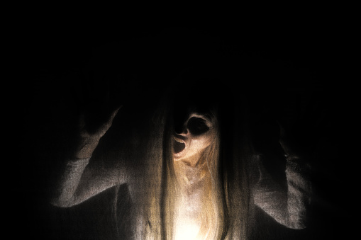 A conceptual image of a creepy woman's soul behind a veil of black looking tortured.
