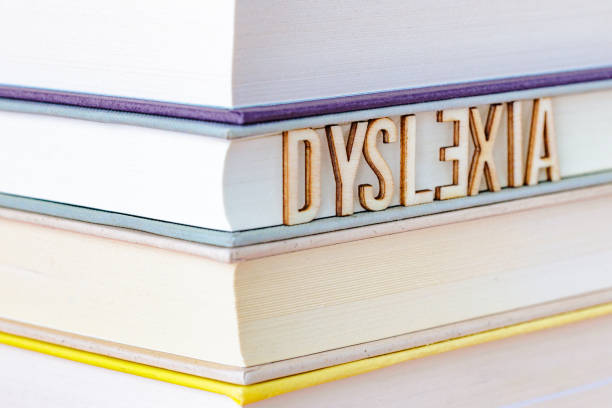 Stack of books with letter tiles spelling the word 'Dyslexia' Close up image of a stack of hardcover books. Propped up against the books are a collection of colored wooden letter tiles that spell out the word 'Dyslexia'. The letter 'E' is the wrong way round to illustrate the concept. misspelled stock pictures, royalty-free photos & images