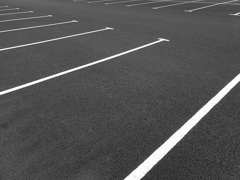 Marking road lines in parking lot, side view. Parking markings, black and white stripes on bitumen. Parking place at store. Empty parking lot.