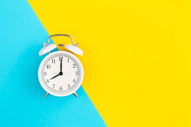 istock White alarm clock on a blue and yellow background, flat lay. 1475090589