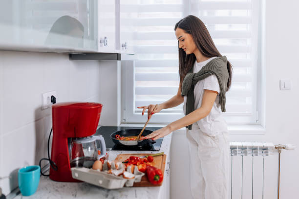 istock Young Woman Cooking Fresh Vegetables in the Kitchen 1475092085