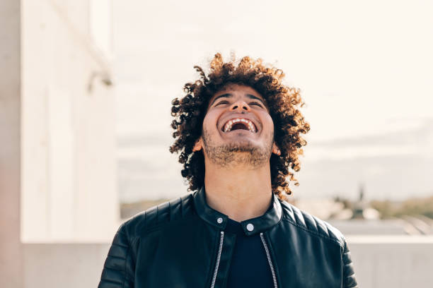 laughing for joy - happy positive curly casual man expressing satisfaction - attitude concept