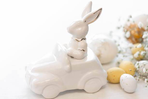 istock Easter background with a ceramic hare in the car and eggs on a white background, 1475093837