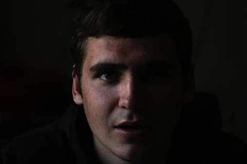 Depressed young man sitting on the floor of the room, screaming and crying.