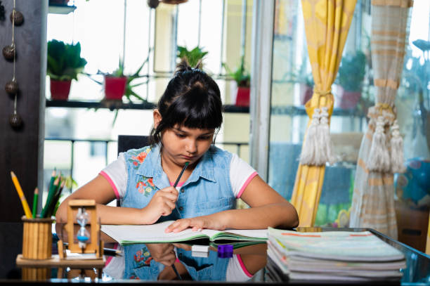 istock Indian little girl studying and writing on notebook 1475097903