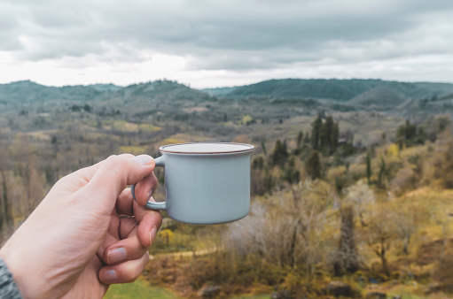hand holding mug on background of mountain landscape