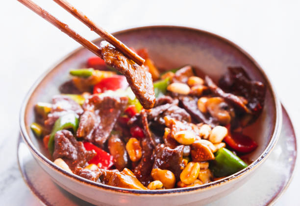 жареное китайское блюдо с нарезанной кубиками говядиной, овощами и арахисом, приготовленным на сковороде. - szechuan cuisine стоковые фото и изображения