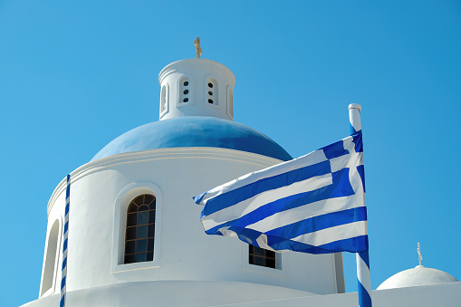 White and blue Greek church with flag and blue sky