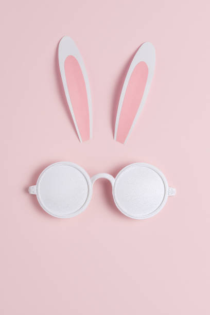 istock Creative Easter concept with bunny ears and white sunglasses on pink background. Minimal Easter concept. 1475102815