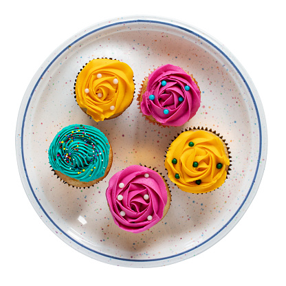 Cupcakes with cream icing on plate isolated on white background, top view.