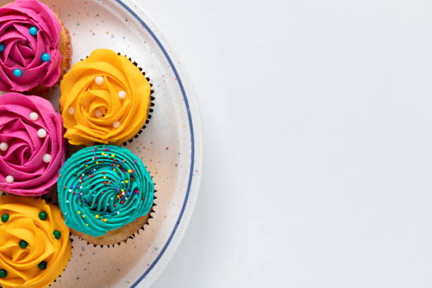 Cupcakes with cream icing on plate on white background, top view with copy space