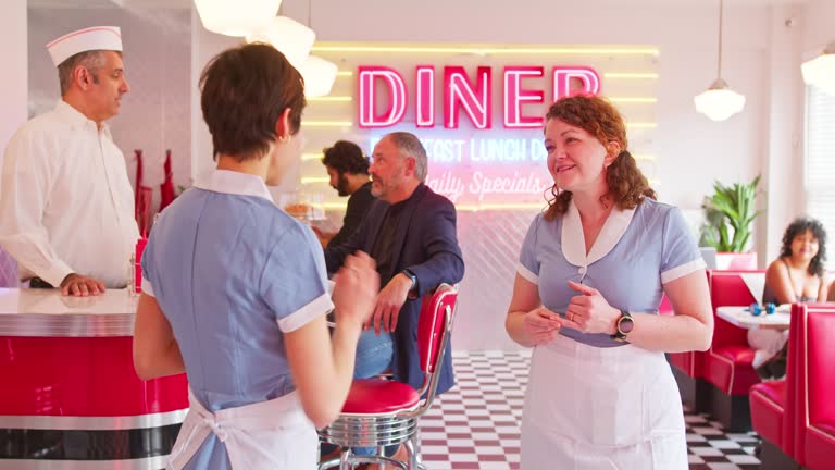 Shot Of Waitresses Talking To Each Other In 1950s Styled Diner