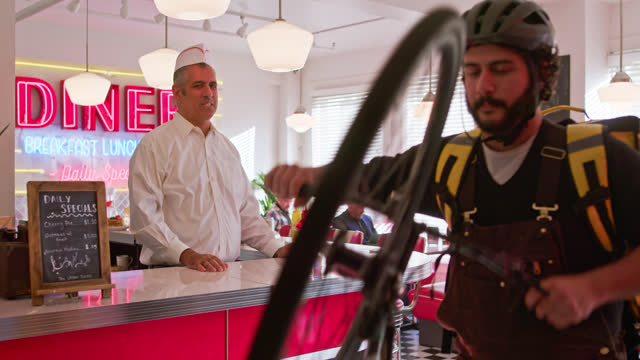 Delivery Person Picks Up Order And Leaves From a 1950s Styled Diner