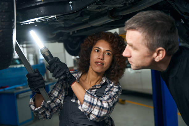 istock Multiracial female mechanic and customer inspecting the car from below 1475104331