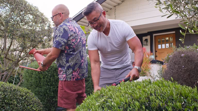 Mixed Race Gay Couple Gardening Outside Their New Home