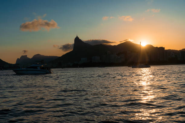 закат в бухте гуанабара, бухта и пляжи рио-де-жанейро, бразилия с ее зданиями, лодками и ландшафтом. отражение неба в море - flamengo стоковые фото и изображения