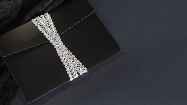 istock black envelope mockup, shot from the top on a black background with copy space. Tied with a silver ribbon. 1475111421