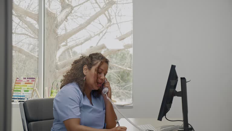 Female doctor consults with colleague via telephone in her office