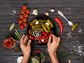 Plate with canned vegetables in hands on a dark background top view