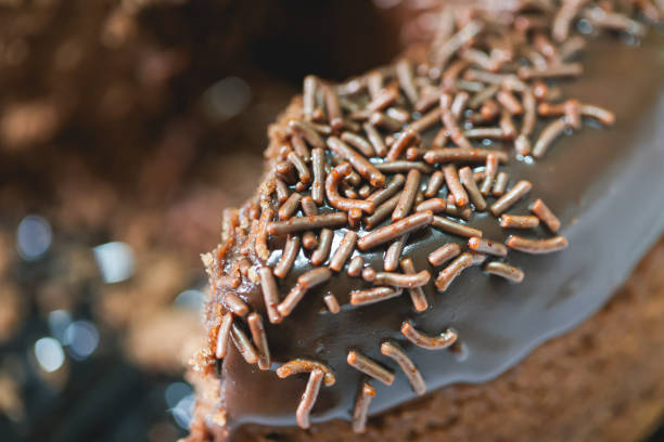 A pre-cut chocolate cake with chocolate frosting and decorated with chocolate sprinkles. Yellow plate. In Brazil it is known as bolo de brigadeiro.