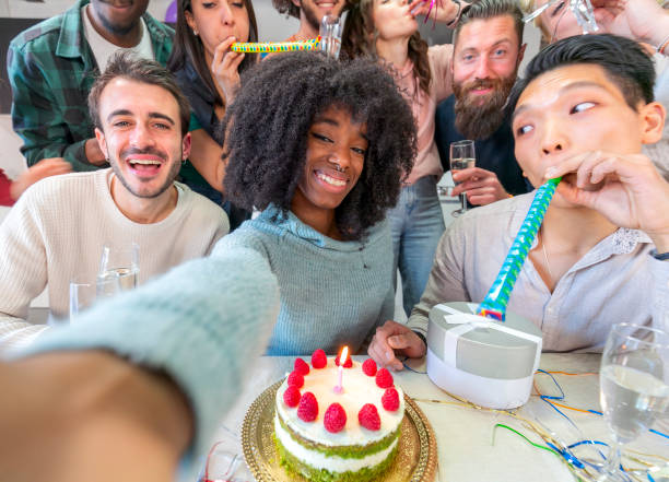 istock Joyful group of  multiethnic friends taking selfie while having birthday party at home, using mobile phone and drinking champagne 1475121568
