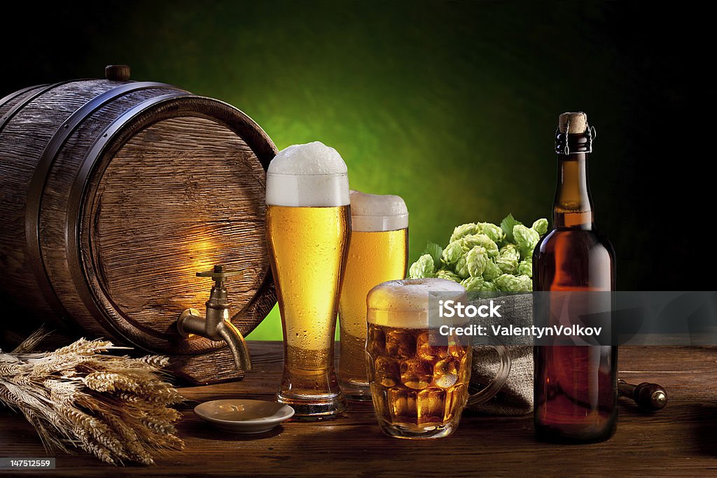 Barrel with beer glasses on a wooden table. Beer barrel with beer glasses on a wooden table. The dark green background. Alcohol - Drink Stock Photo