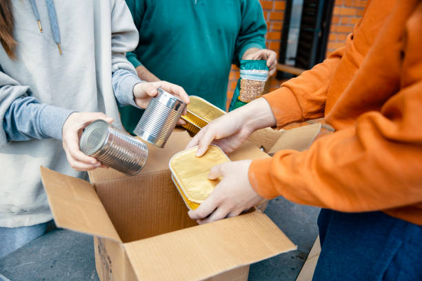 famiglia che disimballa il cibo dalle scatole delle donazioni - community outreach social worker teenager poverty foto e immagini stock