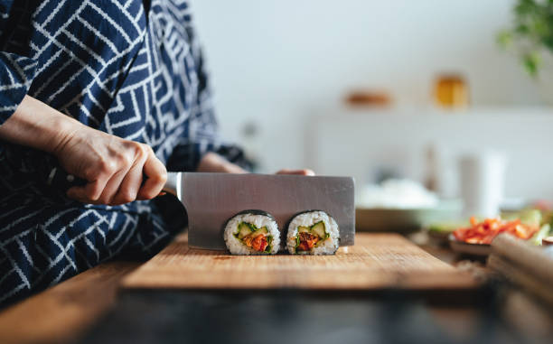 close up photo of woman hands cutting sushi rolls - sushi food vegetarian food japanese cuisine imagens e fotografias de stock