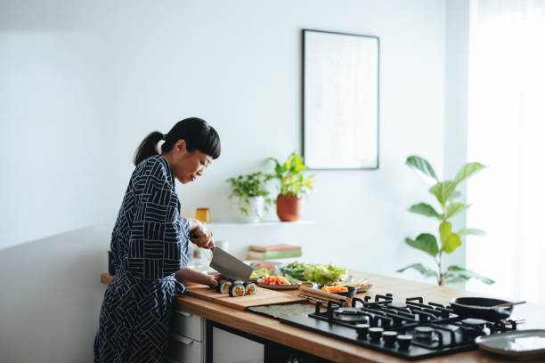 Smiling Woman Cutting Sushi Rolls In The Kitchen
